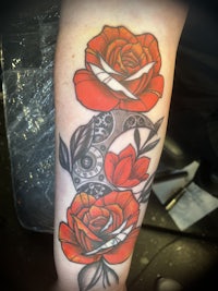 a tattoo with red roses and a clock