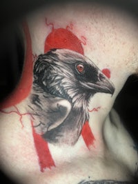 a tattoo of a crow on the back of a man's neck