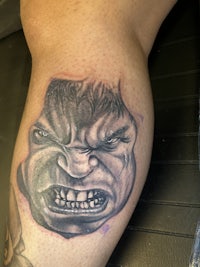 a tattoo of a man's face on his thigh