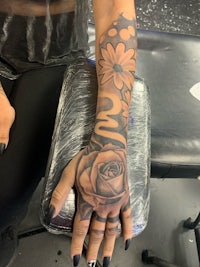 a woman's hand tattooed with roses and flowers