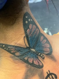 a butterfly tattoo on the back of a woman's neck