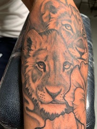 a tattoo of a lion and flowers on the arm