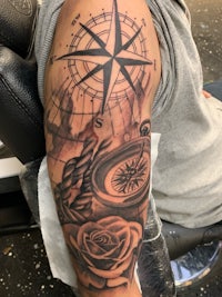 a tattoo of a compass and roses on a man's arm