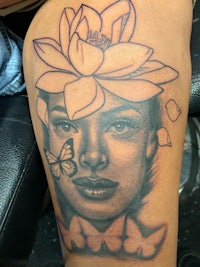 a tattoo of a woman with a flower on her thigh