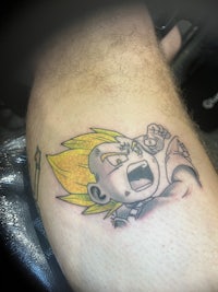 a tattoo of a boy with a yellow tattoo on his thigh