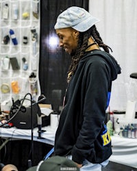 a man with dreadlocks standing in front of a microphone