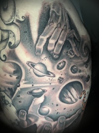 a tattoo of a man with a planet on his back