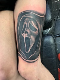 a tattoo of a scream face on a woman's thigh