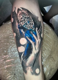 a tattoo of a woman holding a blue shoe