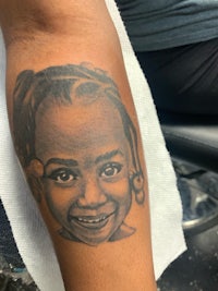 a tattoo of a little girl with a smile on her face